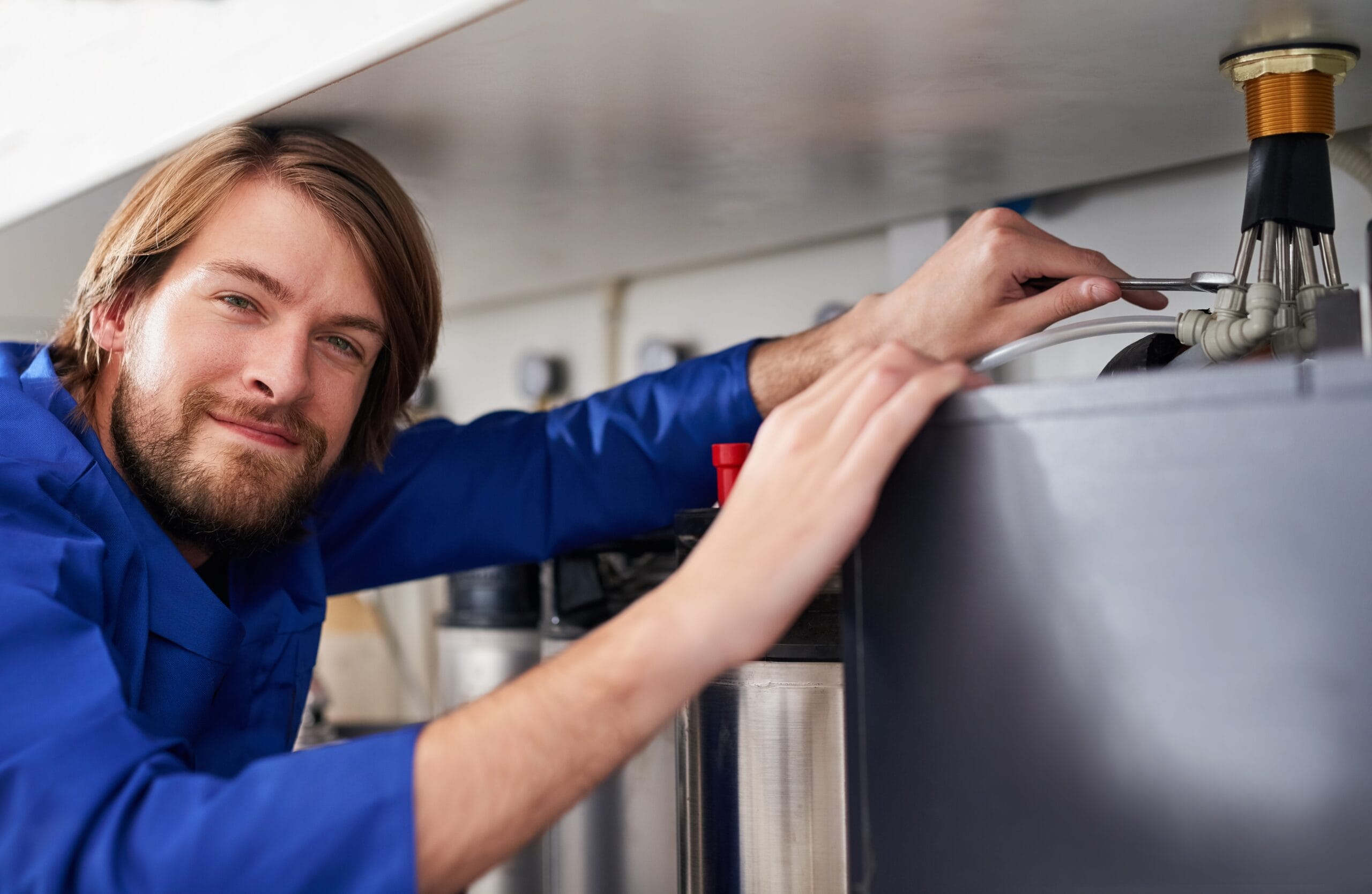 Technician servicing a residential water heater tank in Woodland